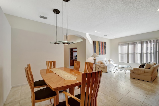 tiled dining room featuring a textured ceiling