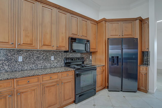 kitchen with light tile patterned floors, brown cabinets, black appliances, tasteful backsplash, and dark stone countertops