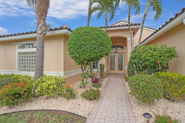 entrance to property with stucco siding, a tile roof, and french doors