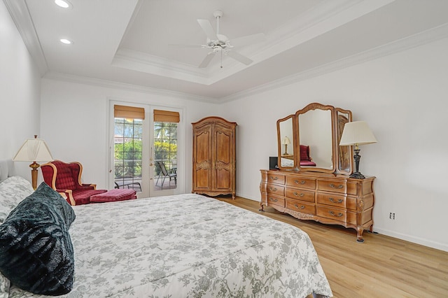 bedroom featuring access to exterior, french doors, crown molding, a raised ceiling, and light wood-style floors