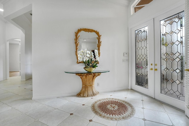 foyer entrance with arched walkways, french doors, baseboards, and light tile patterned floors