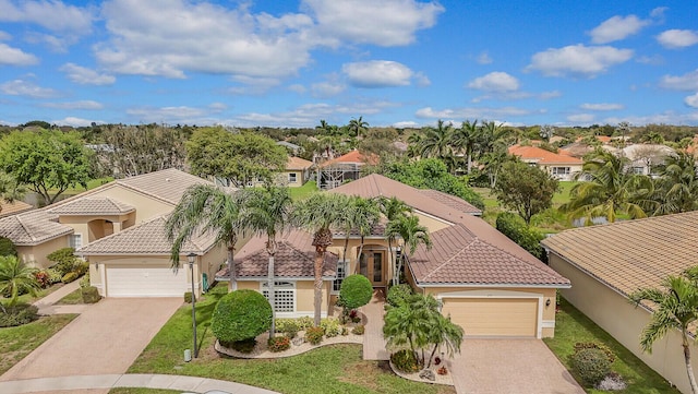 view of front of property featuring a residential view, decorative driveway, a tiled roof, and an attached garage