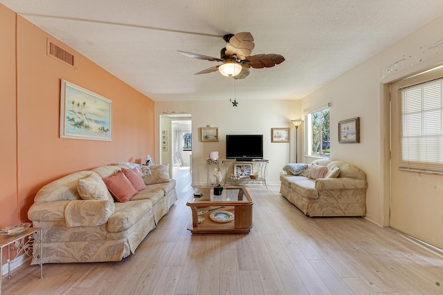 living room featuring ceiling fan, plenty of natural light, a textured ceiling, and light hardwood / wood-style floors