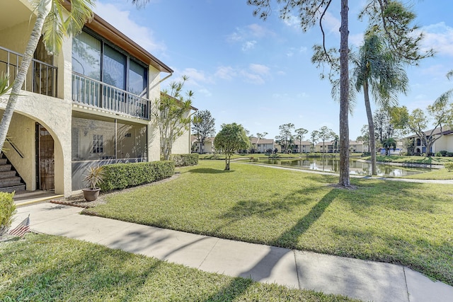 view of property's community with a water view and a lawn