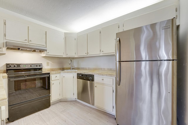 kitchen featuring appliances with stainless steel finishes, white cabinetry, sink, light hardwood / wood-style floors, and a textured ceiling