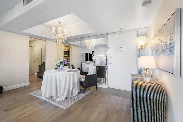 dining room featuring an inviting chandelier, hardwood / wood-style floors, and a raised ceiling