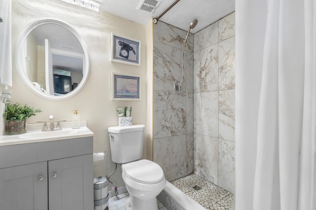 bathroom featuring vanity, toilet, and a tile shower