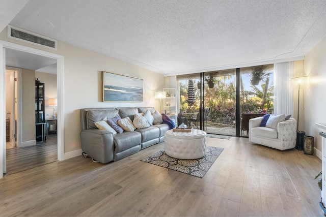 living room with hardwood / wood-style flooring, a textured ceiling, and a wall of windows