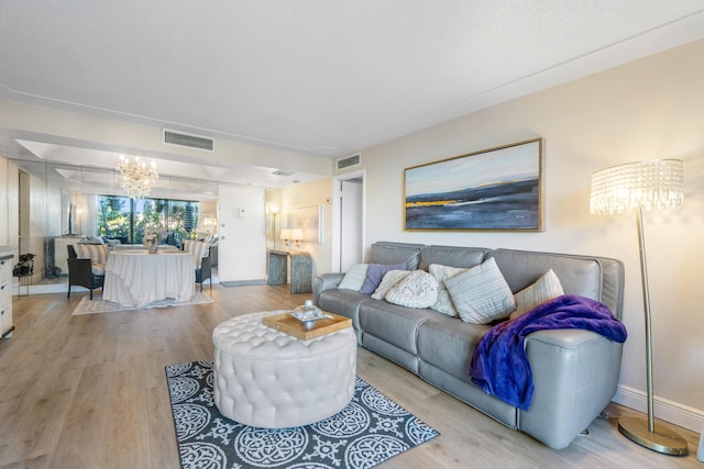 living room with light hardwood / wood-style flooring and a notable chandelier