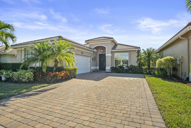 mediterranean / spanish house featuring a garage and a front yard