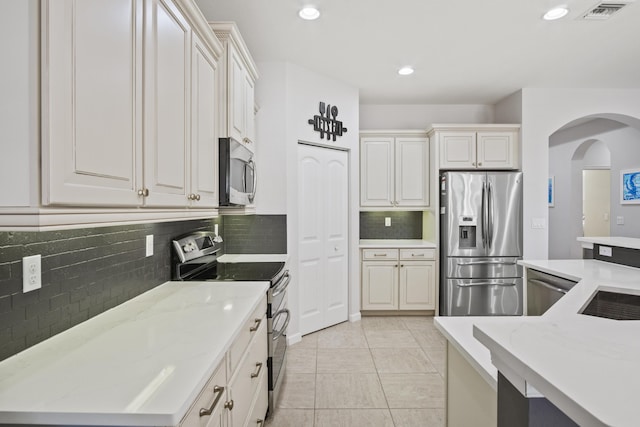 kitchen with light stone countertops, appliances with stainless steel finishes, and decorative backsplash