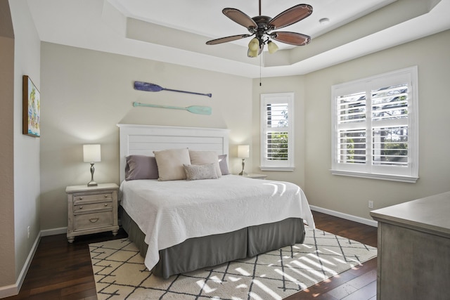 bedroom featuring dark wood-type flooring, ceiling fan, and a tray ceiling