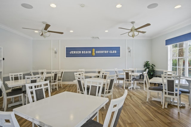 dining space with wood-type flooring, ornamental molding, and ceiling fan