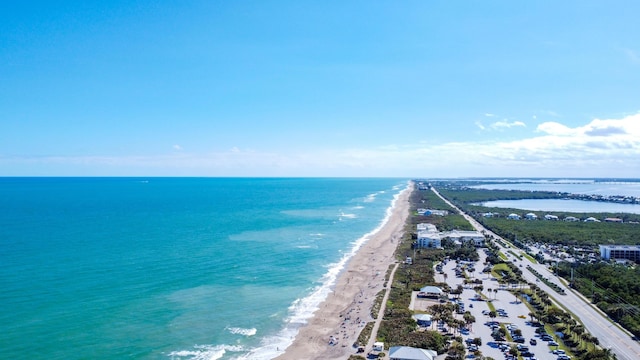 drone / aerial view with a water view and a beach view