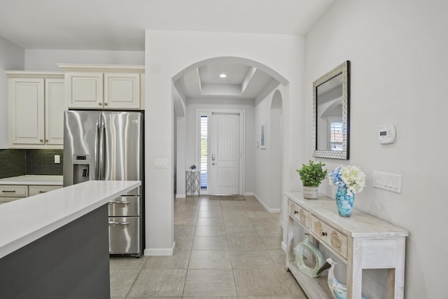 kitchen with tasteful backsplash, a tray ceiling, stainless steel fridge with ice dispenser, and cream cabinets