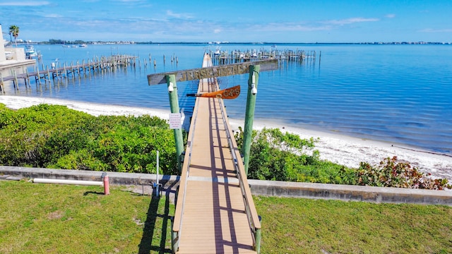 view of dock with a view of the beach, a lawn, and a water view