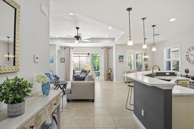 kitchen with pendant lighting, sink, ceiling fan with notable chandelier, and an island with sink