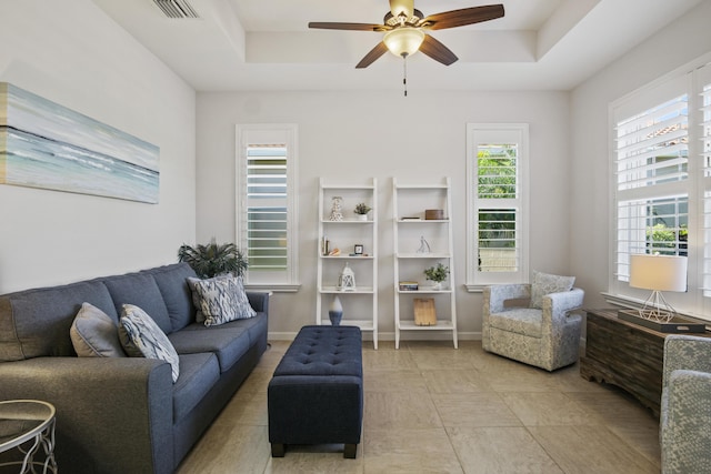 living room with tile patterned flooring, a tray ceiling, and ceiling fan