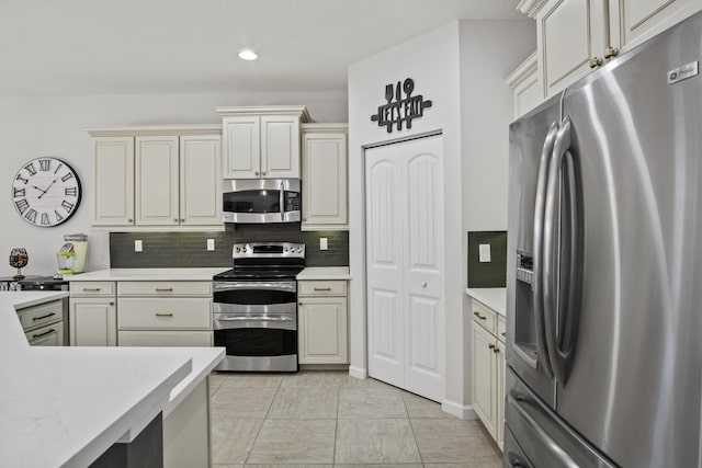 kitchen with stainless steel appliances, light tile patterned floors, decorative backsplash, and cream cabinetry