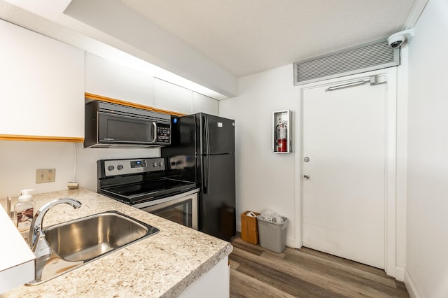 kitchen with hardwood / wood-style flooring, sink, white cabinets, and black appliances