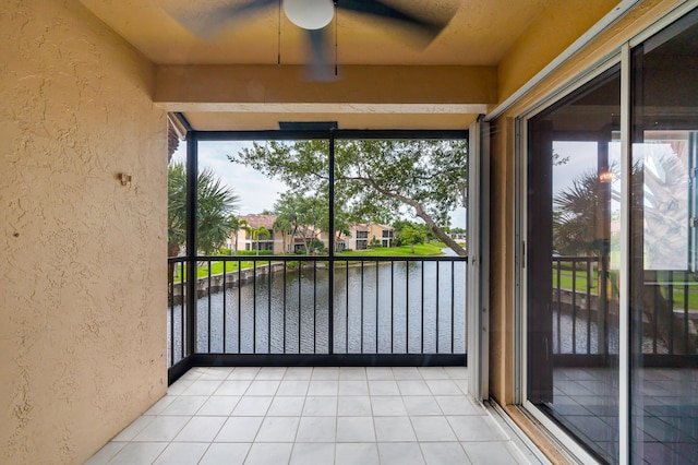 unfurnished sunroom featuring a water view and ceiling fan