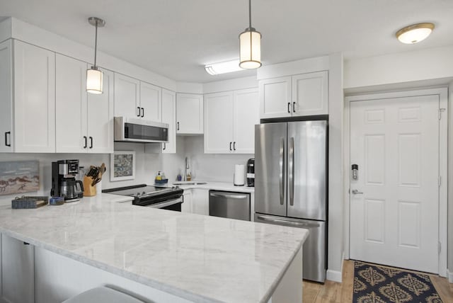 kitchen featuring a sink, white cabinetry, stainless steel appliances, a peninsula, and light stone countertops