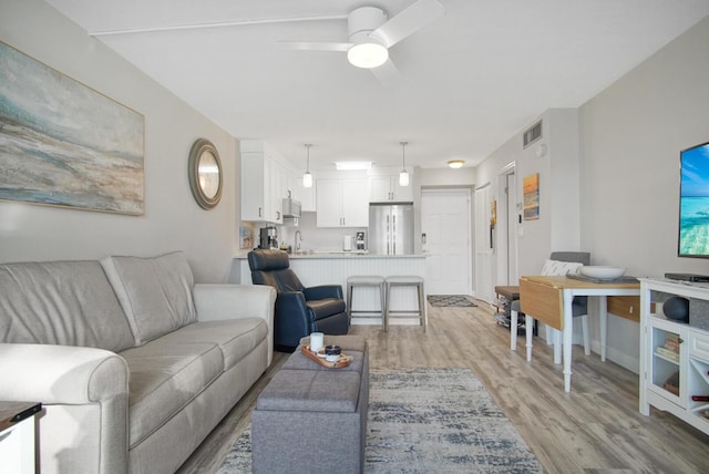 living room featuring visible vents, light wood-type flooring, and ceiling fan