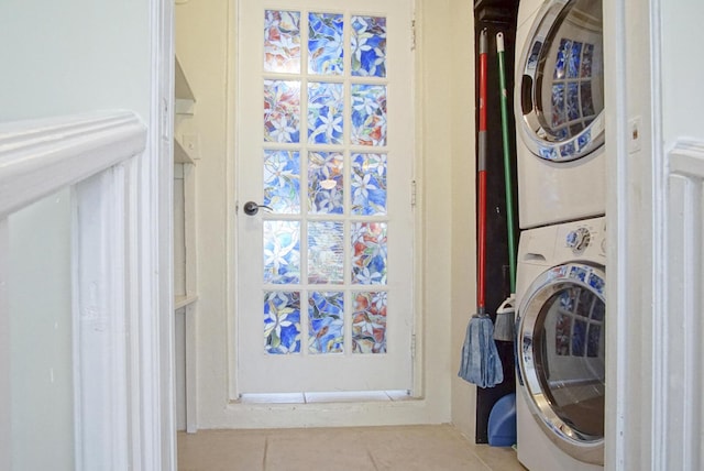 laundry room featuring stacked washer and dryer and light tile patterned floors