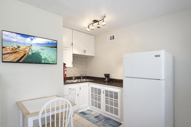 kitchen featuring light tile patterned flooring, sink, white cabinetry, white fridge, and decorative backsplash