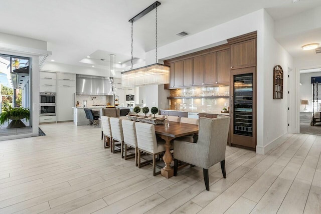 dining area with light hardwood / wood-style flooring and beverage cooler