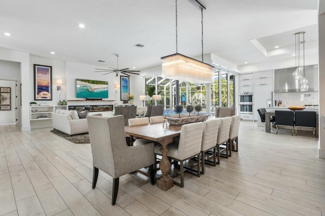 dining room with light hardwood / wood-style flooring, a raised ceiling, and ceiling fan