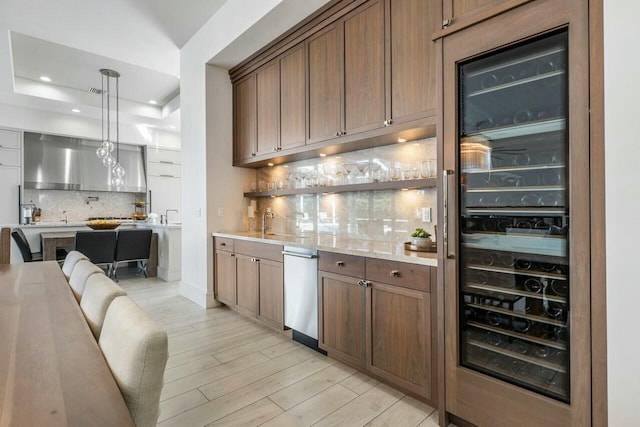 bar with wine cooler, pendant lighting, light stone countertops, light hardwood / wood-style floors, and backsplash