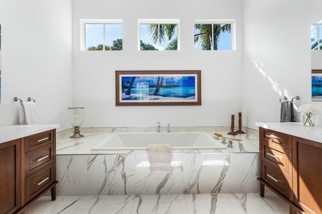 bathroom with vanity, a relaxing tiled tub, and a healthy amount of sunlight