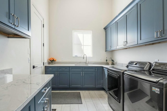 laundry room with cabinets, washer and dryer, sink, and light hardwood / wood-style flooring