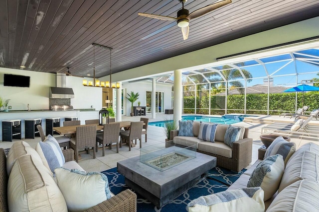 view of patio with exterior bar, a lanai, and an outdoor living space with a fire pit