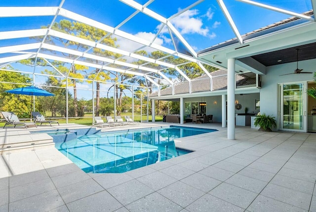 view of pool with a patio area, exterior kitchen, ceiling fan, and glass enclosure