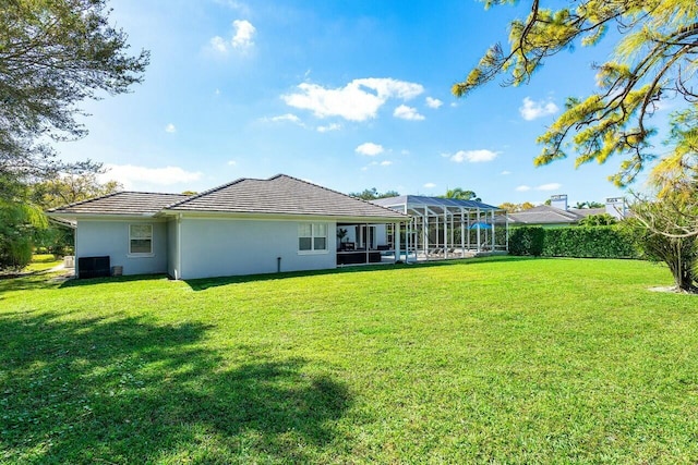 rear view of property featuring a lanai and a lawn