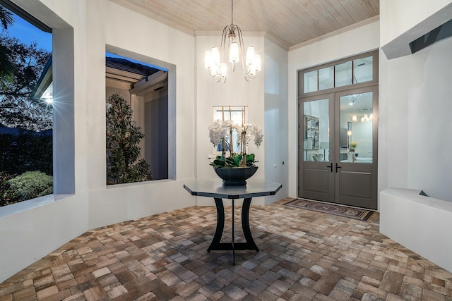 foyer entrance featuring french doors, ornamental molding, an inviting chandelier, and wooden ceiling