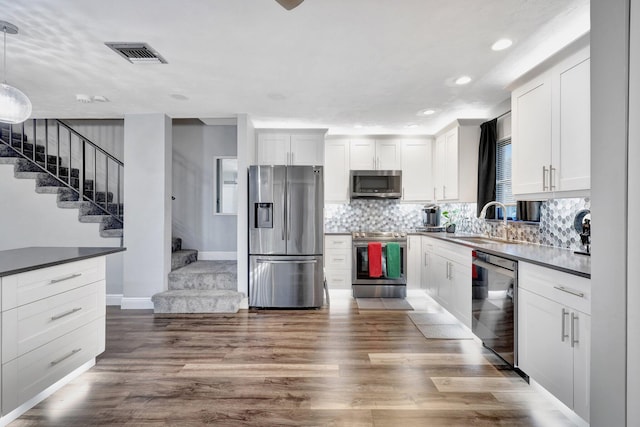 kitchen featuring white cabinetry, sink, decorative light fixtures, and appliances with stainless steel finishes