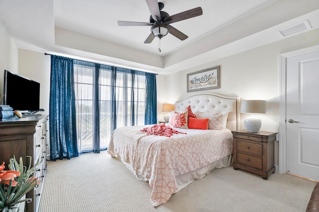 carpeted bedroom featuring a tray ceiling and ceiling fan