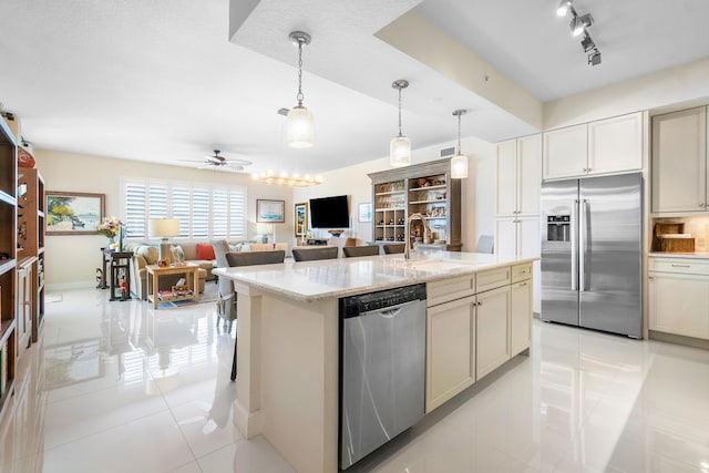 kitchen featuring light tile patterned flooring, decorative light fixtures, sink, light stone counters, and stainless steel appliances