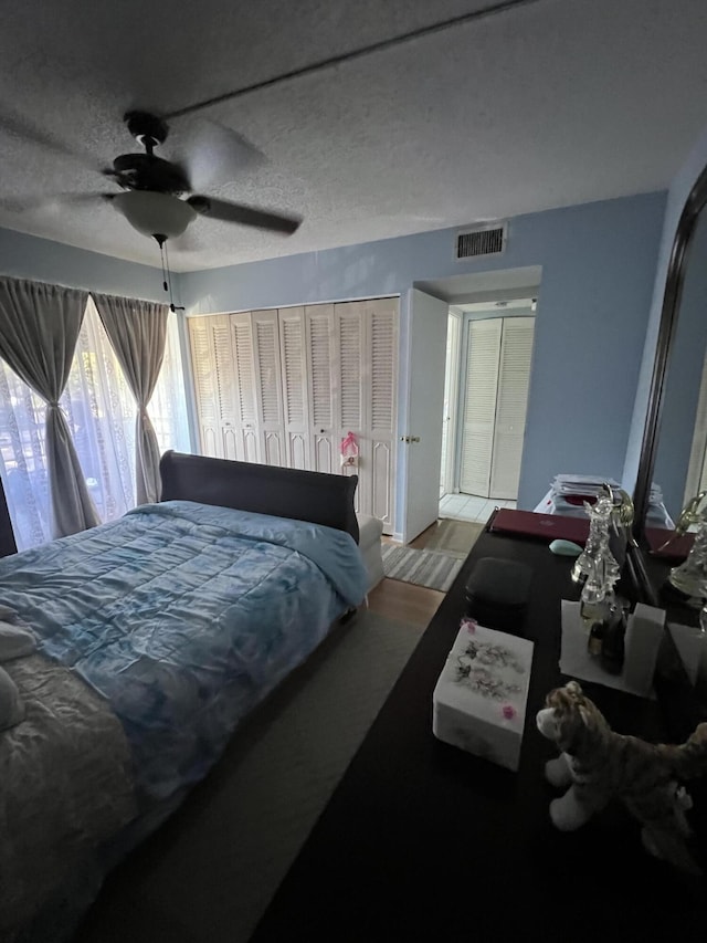 bedroom featuring ceiling fan, hardwood / wood-style flooring, and a textured ceiling