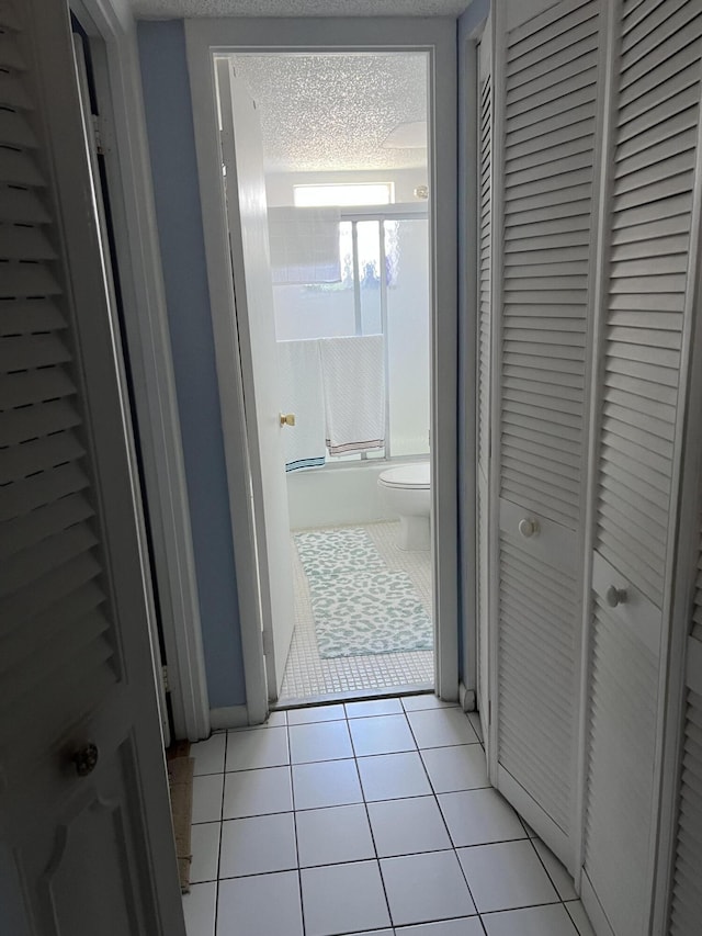 hall with light tile patterned flooring and a textured ceiling