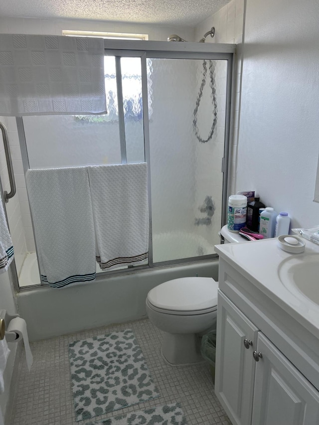 full bathroom with combined bath / shower with glass door, tile patterned flooring, vanity, toilet, and a textured ceiling