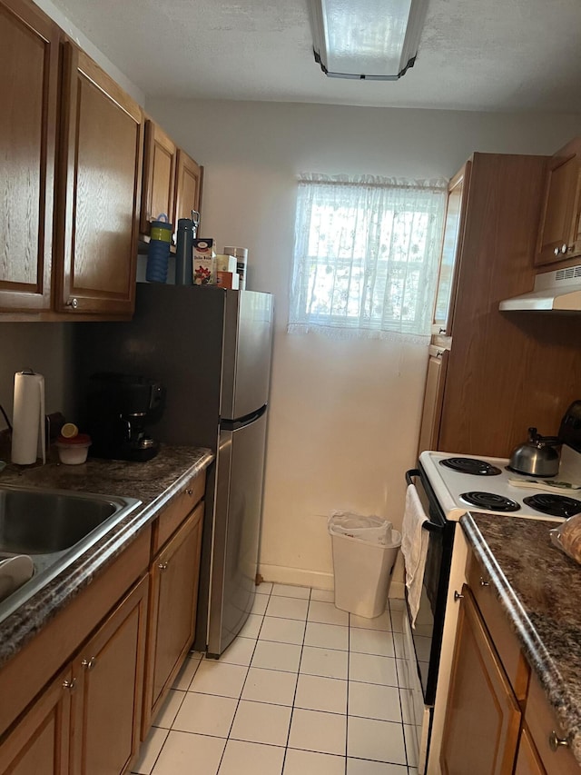 kitchen featuring electric stove, light tile patterned floors, stainless steel fridge, and sink