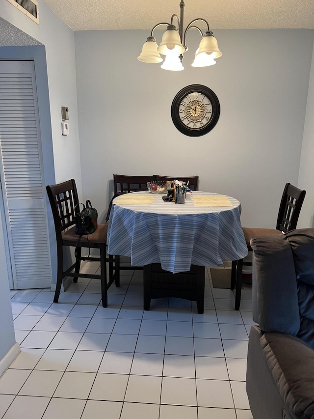 dining room with light tile patterned flooring, a textured ceiling, and an inviting chandelier