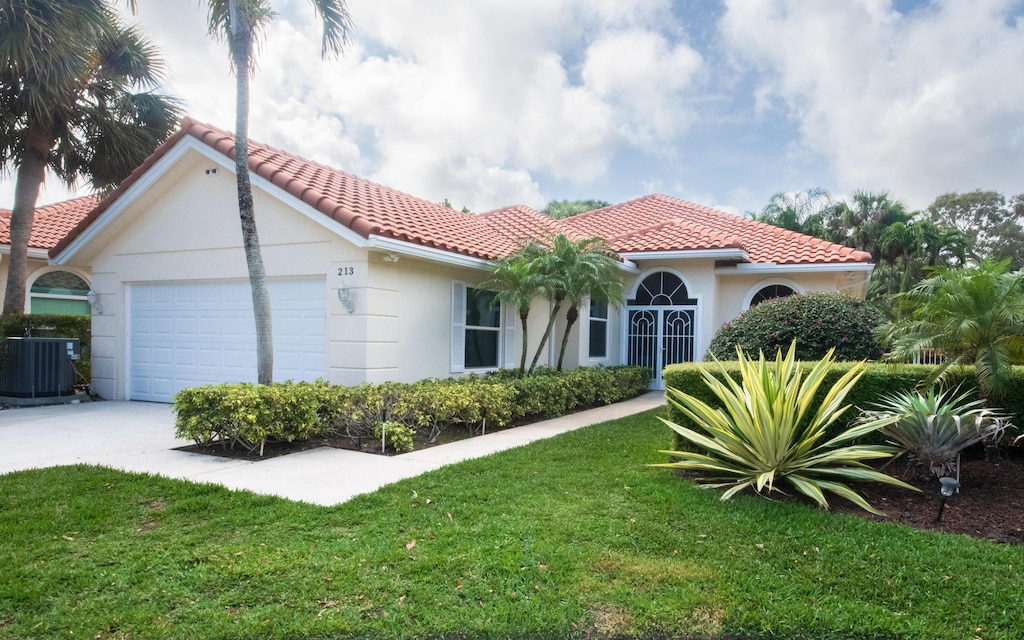 mediterranean / spanish home with a garage, a front yard, and central air condition unit