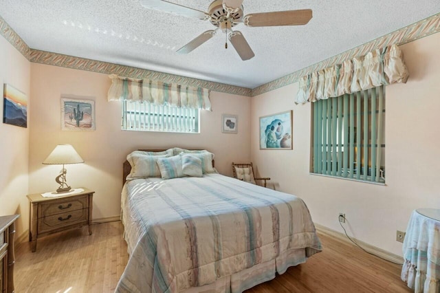 bedroom with ceiling fan, light hardwood / wood-style floors, and a textured ceiling