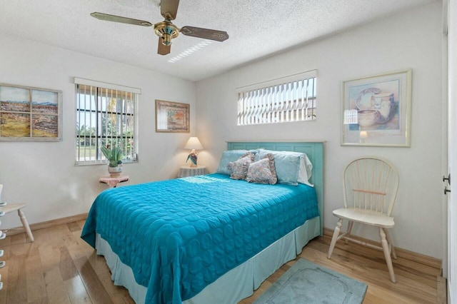 bedroom featuring ceiling fan, light hardwood / wood-style flooring, and a textured ceiling