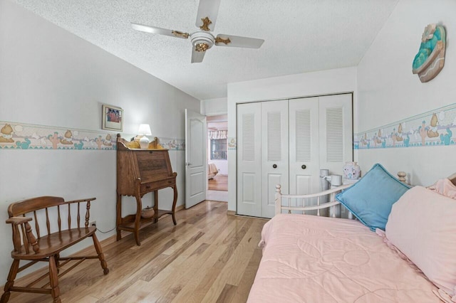 bedroom featuring ceiling fan, a textured ceiling, a closet, and light hardwood / wood-style flooring